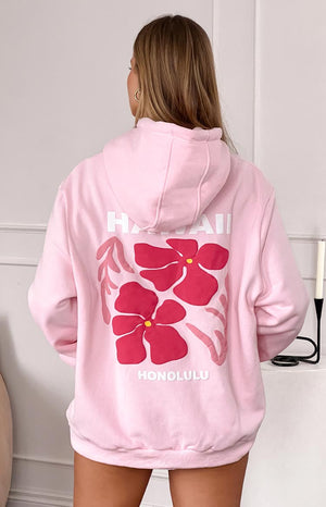girl wearing a pink hoodie with a pink and white honolulu hawaii graphic on the back