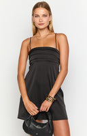 blonde model wearing a black satin mini party dress with pin tuck details at the bust
