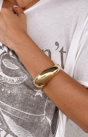 model wearing oversized gold cuff bracelet and graphic tee