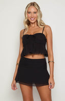 brunette model wearing a black chiffon mini skirt with layered details and a gathered waist